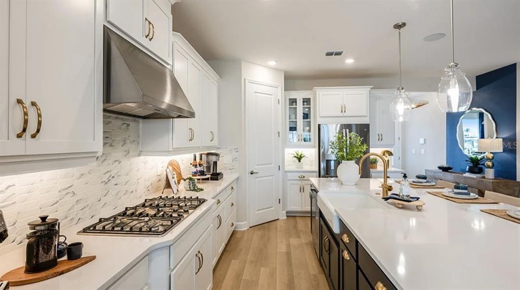 A kitchen features white upper cabinets, dark lower cabinets, a gas range, and a large island — 5292 GOLDFINCH DRIVE, ST CLOUD, FL