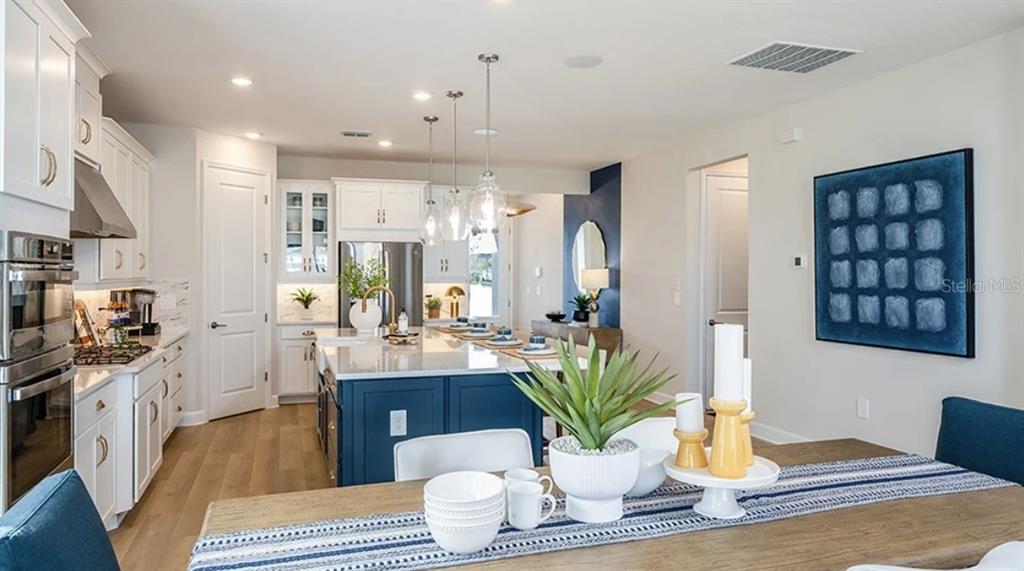 A kitchen with a blue island and white cabinets opens into a dining area — 5292 GOLDFINCH DRIVE, ST CLOUD, FL