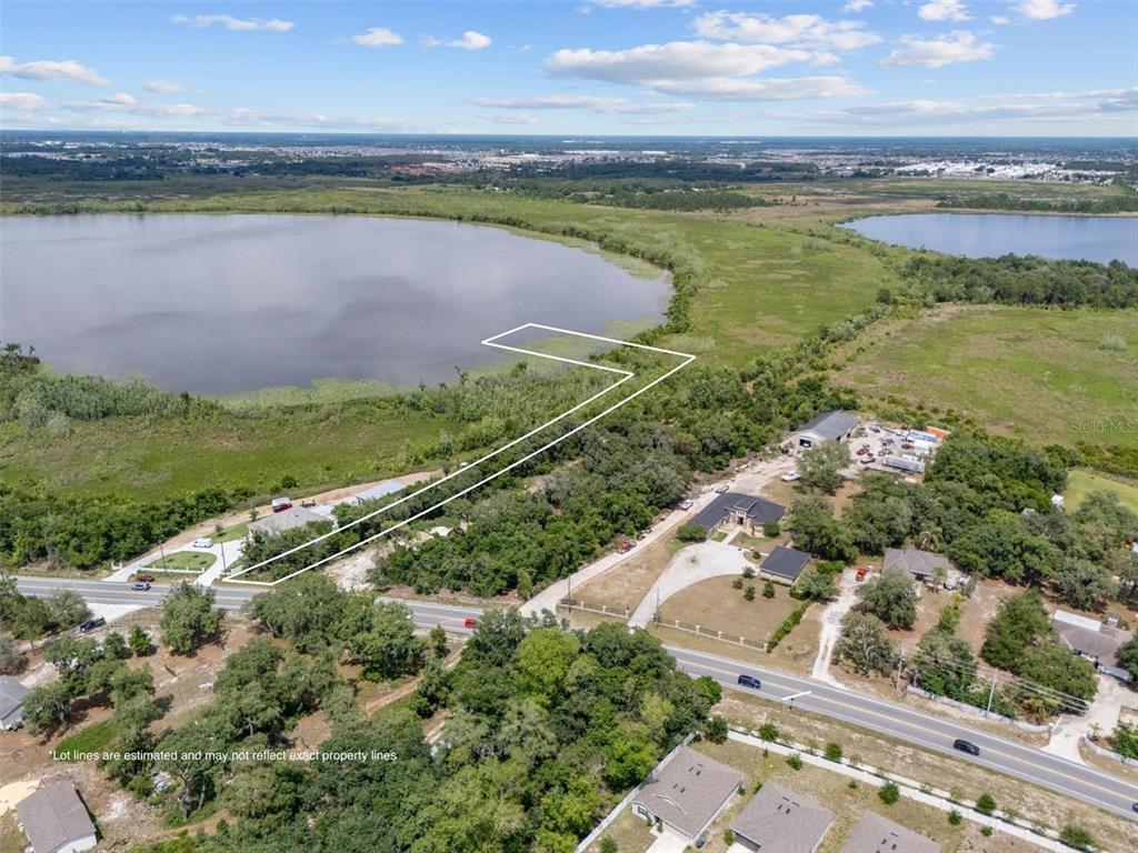 An aerial view shows a plot of land outlined in white bordering a large lake — 0 POLK CITY ROAD, HAINES CITY, FL