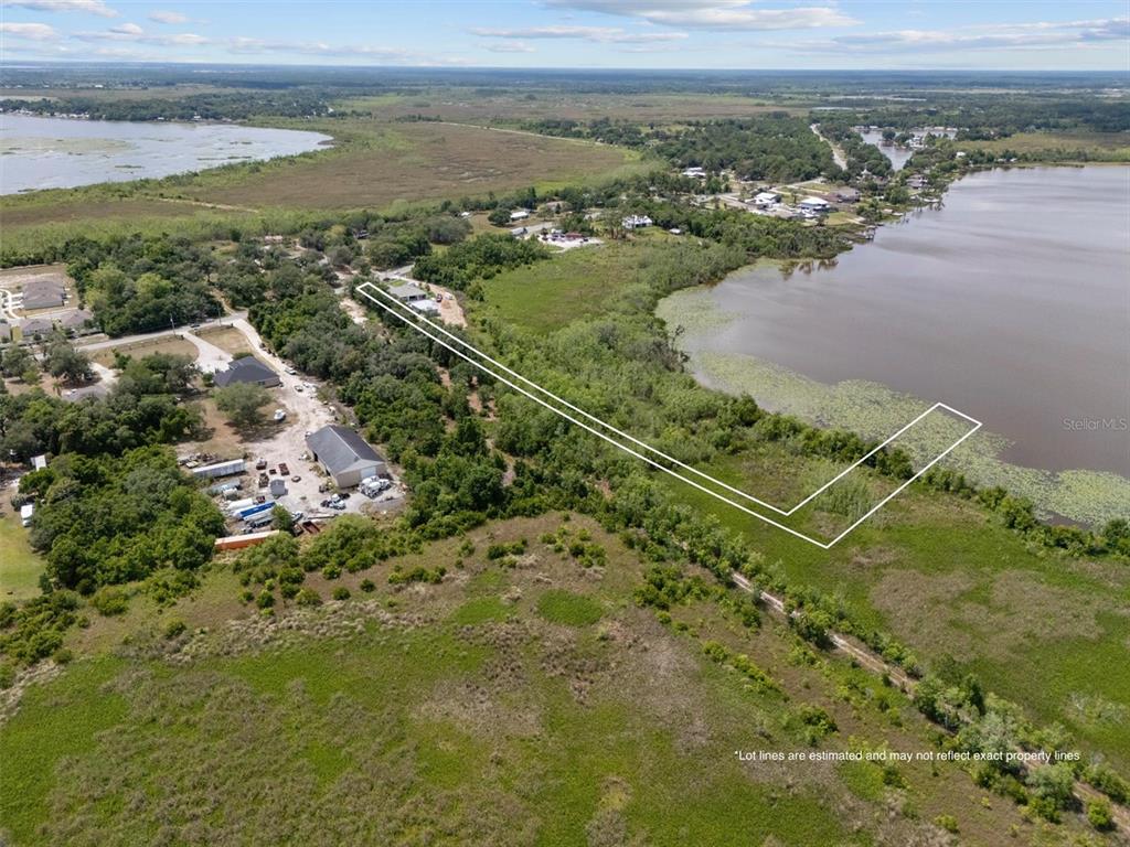 An aerial view shows a vacant lot outlined in white bordering a large lake — 0 POLK CITY ROAD, HAINES CITY, FL
