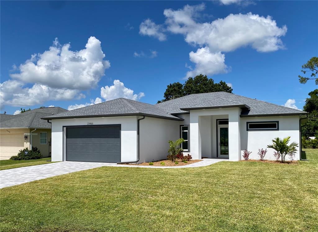 A modern single-story house with a gray garage, white stucco exterior, and a paved driveway — 23466 GARRETT AVENUE, PORT CHARLOTTE, FL