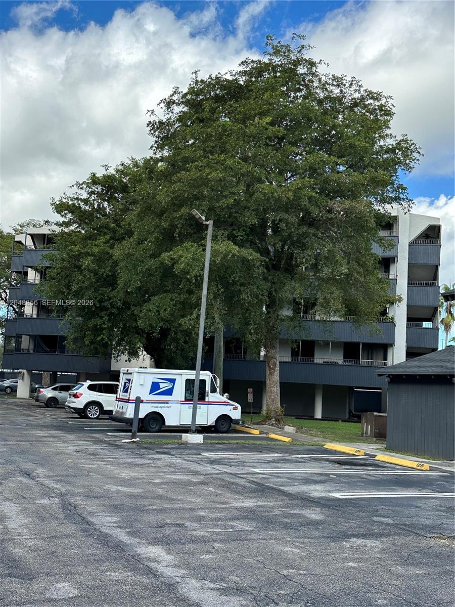 A multi-story apartment building stands behind a parking lot with a USPS mail truck — 16220 NW 2nd Ave # 412, Miami FL 33169, MIAMI, FL