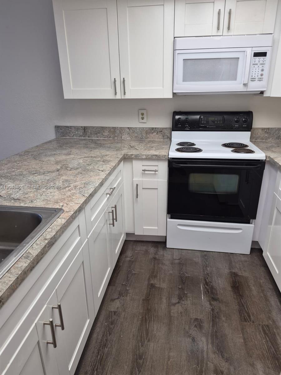 A kitchen features white cabinets, a black electric stove, and a stone-patterned laminate countertop — 16220 NW 2nd Ave # 412, Miami FL 33169, MIAMI, FL