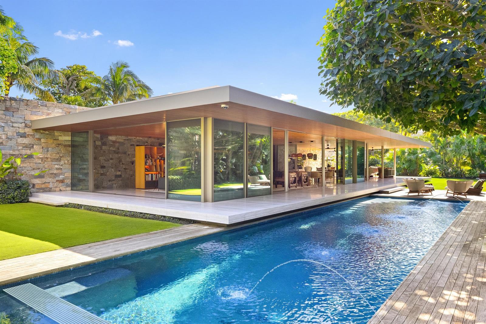 A modern house with glass walls and stone accents overlooks a swimming pool and lawn — 195 Via Marina, Palm Beach FL 33480, PALM BEACH, FL