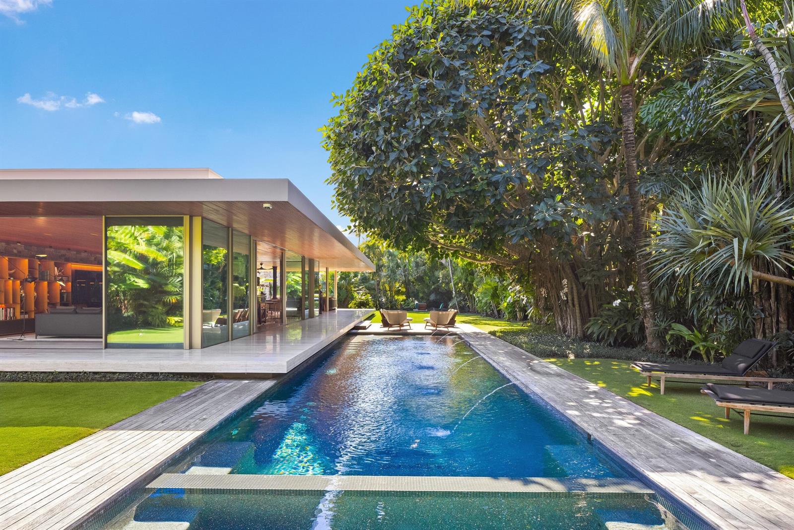 A modern house with floor-to-ceiling windows overlooks a long swimming pool and lush garden — 195 Via Marina, Palm Beach FL 33480, PALM BEACH, FL