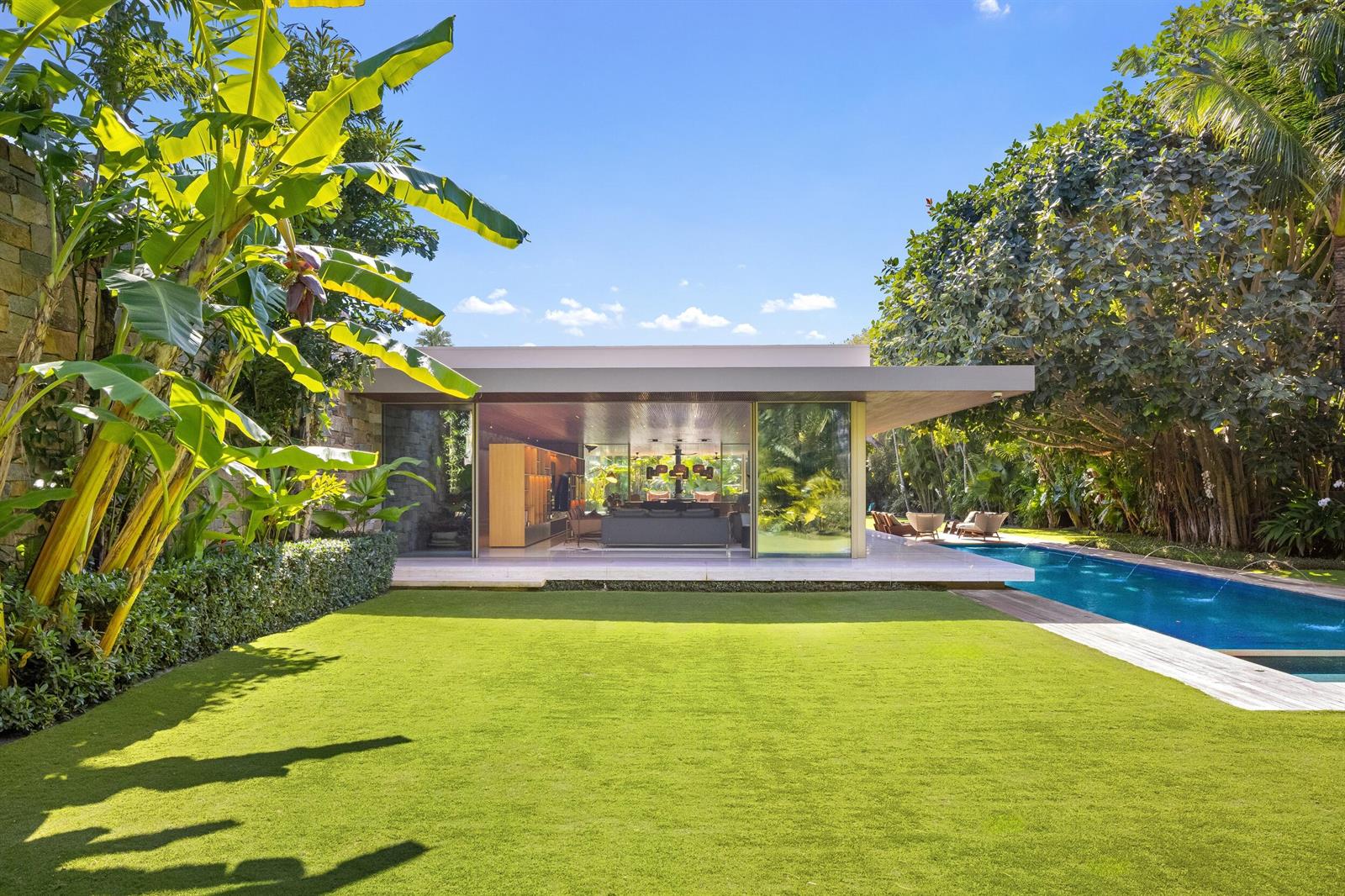 A modern house with floor-to-ceiling glass walls overlooks a green lawn and a swimming pool — 195 Via Marina, Palm Beach FL 33480, PALM BEACH, FL