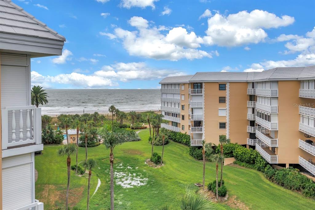 An elevated view of a grassy courtyard between two beachside apartment buildings under a blue sky — 6500 SUNSET WAY UNIT 505, ST PETE BEACH, FL