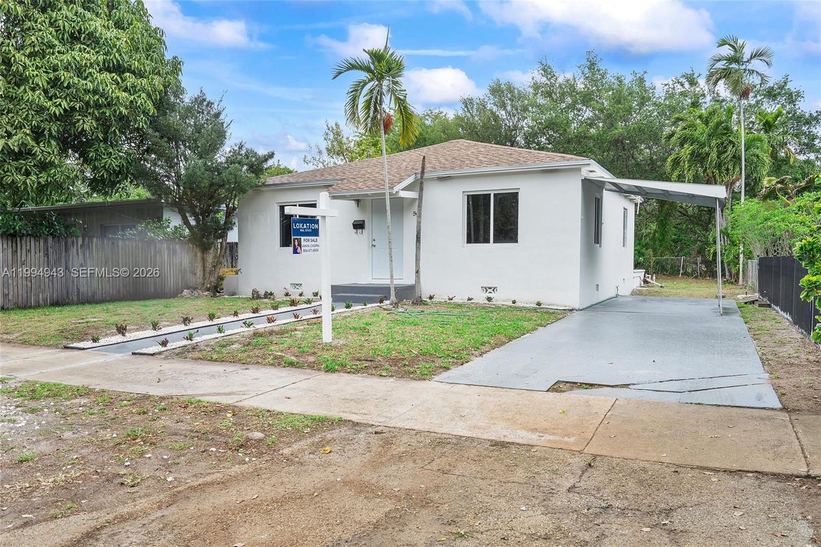 A white single-story house features a front lawn, a driveway with a carport, and landscaping — 511 NE 131st St, North Miami FL 33161, NORTH MIAMI, FL