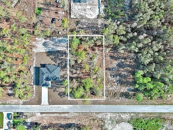 An aerial view shows a rectangular plot of land outlined in white next to a house — 634 LADD STREET, LEHIGH ACRES, FL