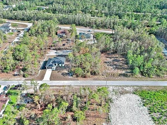 An aerial view shows a house with a driveway surrounded by trees and vacant land — 634 LADD STREET, LEHIGH ACRES, FL