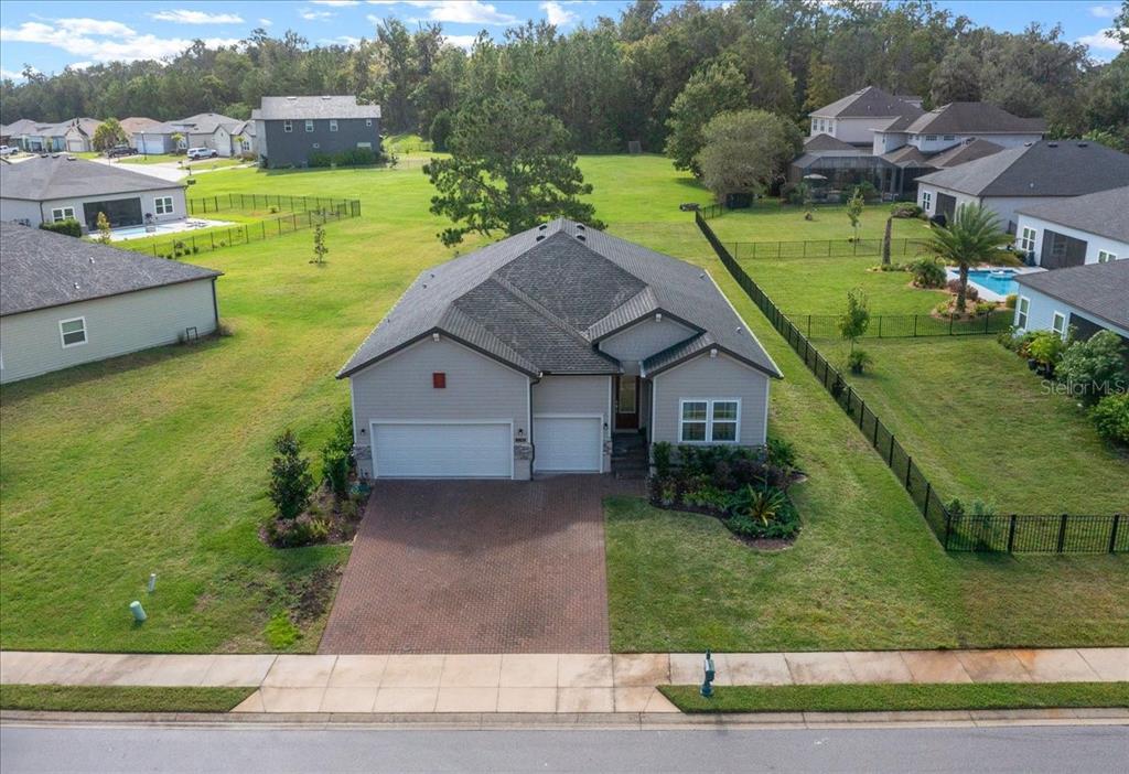 An aerial view of a single-story suburban house with a brick driveway and fenced yard — 1130 SE 42ND ROAD, OCALA, FL