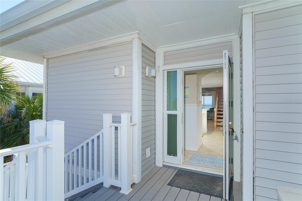 An open front door reveals a view into a home with light-colored flooring and stairs — 7494 PALM ISLAND DRIVE UNIT 2224, PLACIDA, FL