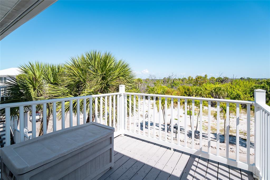 A wooden deck with a storage chest overlooks palm trees and a sandy landscape — 7494 PALM ISLAND DRIVE UNIT 2224, PLACIDA, FL