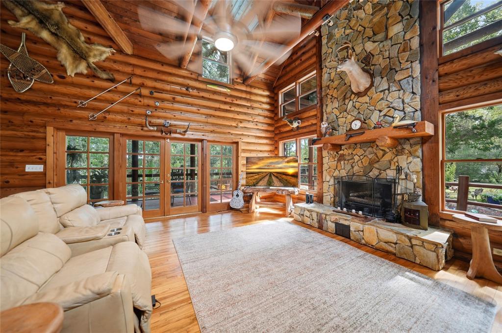 A rustic log cabin living room features a stone fireplace, vaulted ceiling, and leather furniture — 8199 W PINOAK COURT, HOMOSASSA, FL