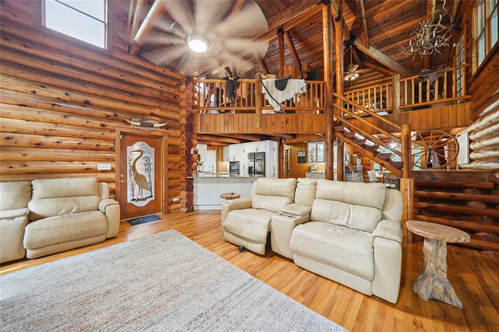 A rustic log cabin living room features a loft, wooden walls, and leather reclining sofas — 8199 W PINOAK COURT, HOMOSASSA, FL