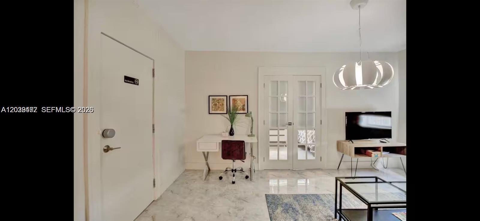 A room features a white desk, French doors, a television on a stand, and marble flooring — 174 NE 47th St # 202, Miami FL 33137, MIAMI, FL