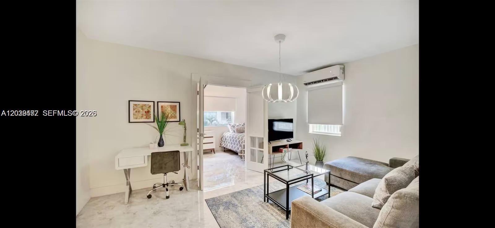 A living room features a desk, a sofa, a coffee table, and a doorway to a bedroom — 174 NE 47th St # 202, Miami FL 33137, MIAMI, FL