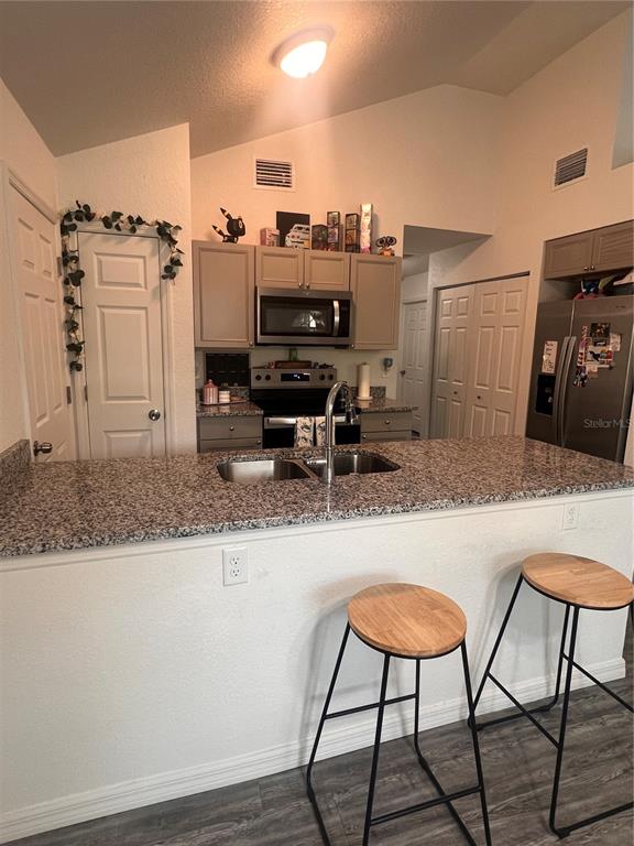 A kitchen features a granite breakfast bar, stainless steel appliances, and two wooden bar stools — 10444 SE 126TH STREET, BELLEVIEW, FL