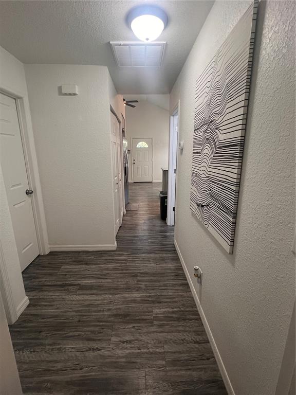 A hallway with wood-look flooring leads toward an exterior door in a white-walled home — 10444 SE 126TH STREET, BELLEVIEW, FL