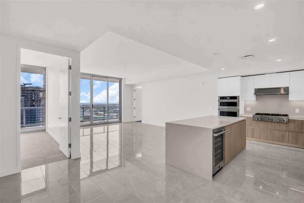 A modern kitchen with a stone island and white cabinets opens into a bright living area — 400 CENTRAL AVENUE UNIT 2605, ST PETERSBURG, FL
