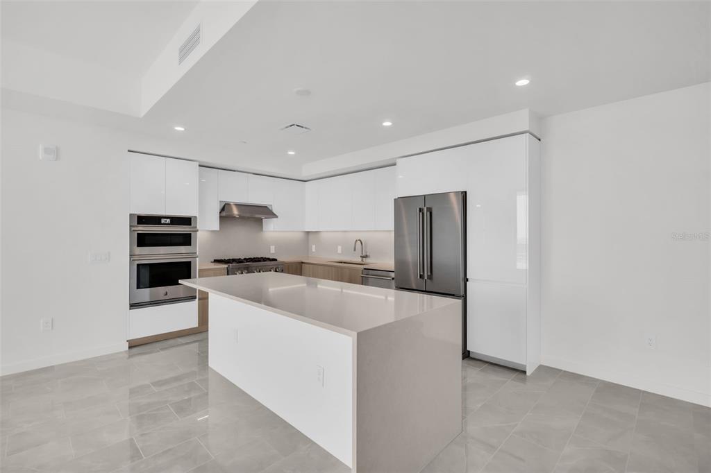 A modern kitchen features white cabinetry, a large quartz island, and stainless steel appliances — 400 CENTRAL AVENUE UNIT 2605, ST PETERSBURG, FL