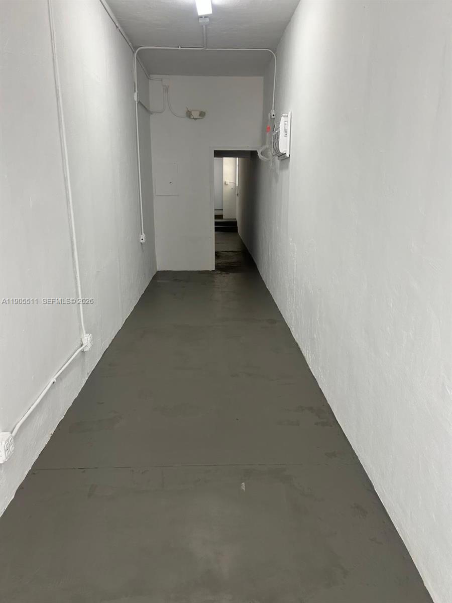 A narrow, empty hallway features white walls, a gray floor, and an overhead light fixture — 1024 71st St, Miami Beach FL 33141, MIAMI BEACH, FL