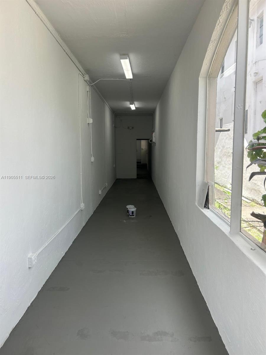 A narrow, empty hallway features white walls, a gray floor, and two overhead fluorescent lights — 1024 71st St, Miami Beach FL 33141, MIAMI BEACH, FL