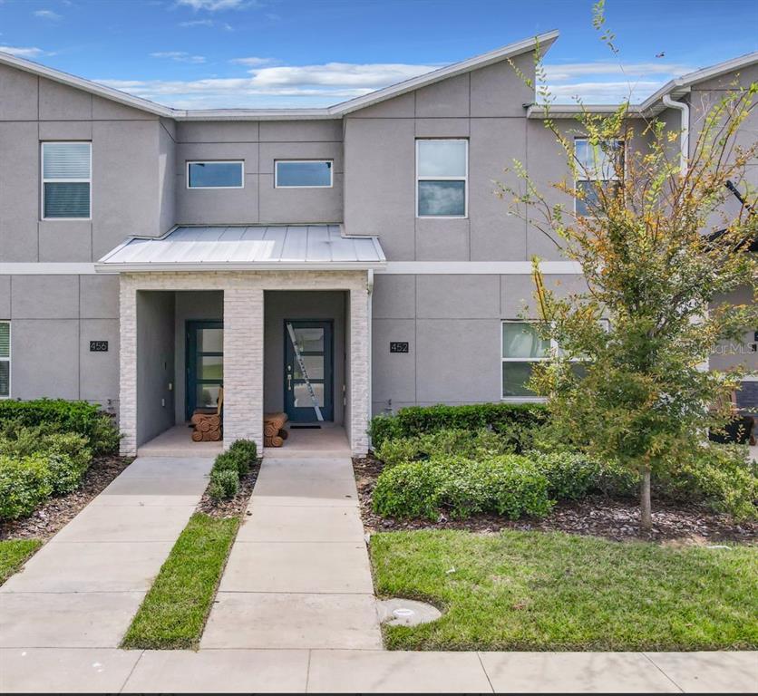 A two-story gray townhouse exterior features two front entrances with stone accents and concrete walkways — 452 OCEAN COURSE AVENUE, DAVENPORT, FL