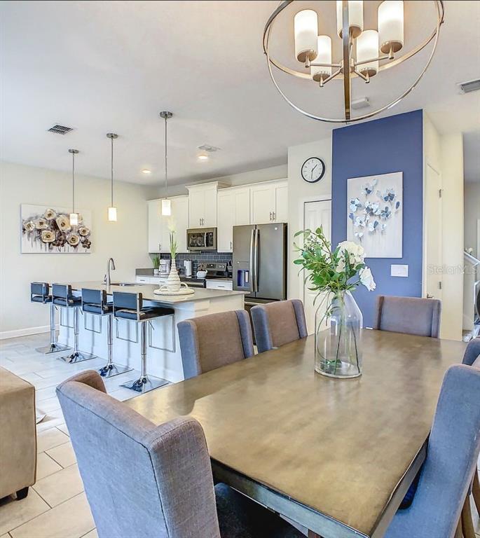 A dining area with a table and chairs opens into a kitchen with an island — 452 OCEAN COURSE AVENUE, DAVENPORT, FL