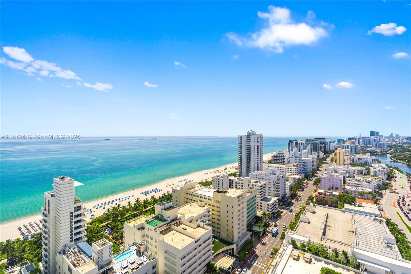 An elevated view shows a beach, ocean, and city skyline under a clear blue sky — 4401 Collins Ave # 2712, Miami Beach FL 33140, MIAMI BEACH, FL