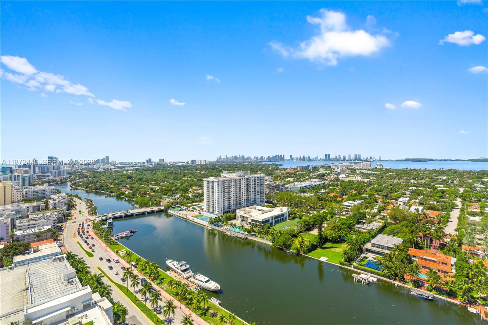 An aerial view shows a waterway, a bridge, residential buildings, and a distant city skyline — 4401 Collins Ave # 2712, Miami Beach FL 33140, MIAMI BEACH, FL