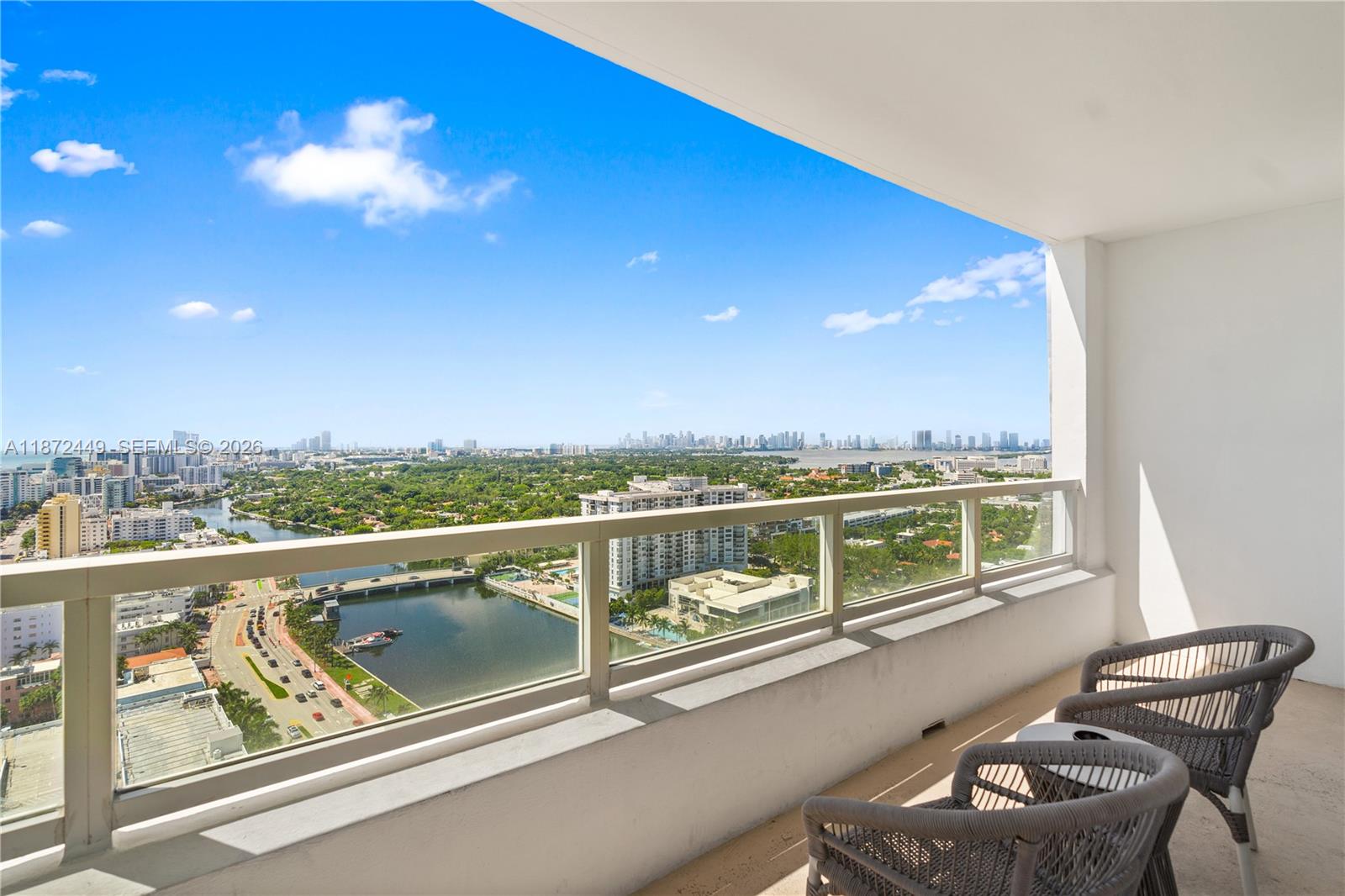 A high-rise balcony features two gray chairs overlooking a city skyline and a waterway — 4401 Collins Ave # 2712, Miami Beach FL 33140, MIAMI BEACH, FL