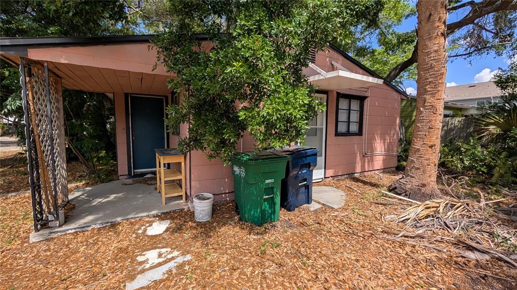 An exterior view of a small, pink house with a covered porch and two trash cans — 2801 W CLEVELAND STREET, TAMPA, FL