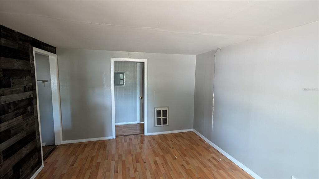 A room with light-colored walls, wood-look flooring, and a dark wood-paneled accent wall — 2801 W CLEVELAND STREET, TAMPA, FL