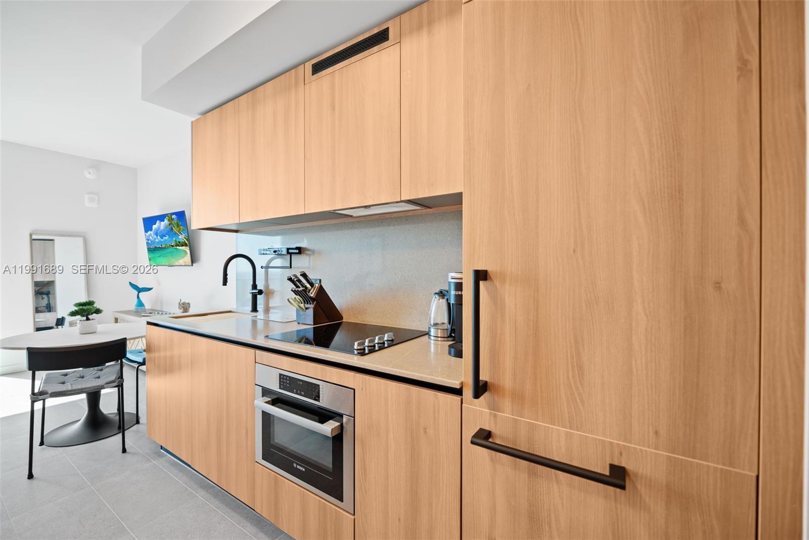 A modern kitchen features light wood cabinetry, a black faucet, and a built-in oven — 121 NE 5 ST # 3507, Miami FL 33132, MIAMI, FL