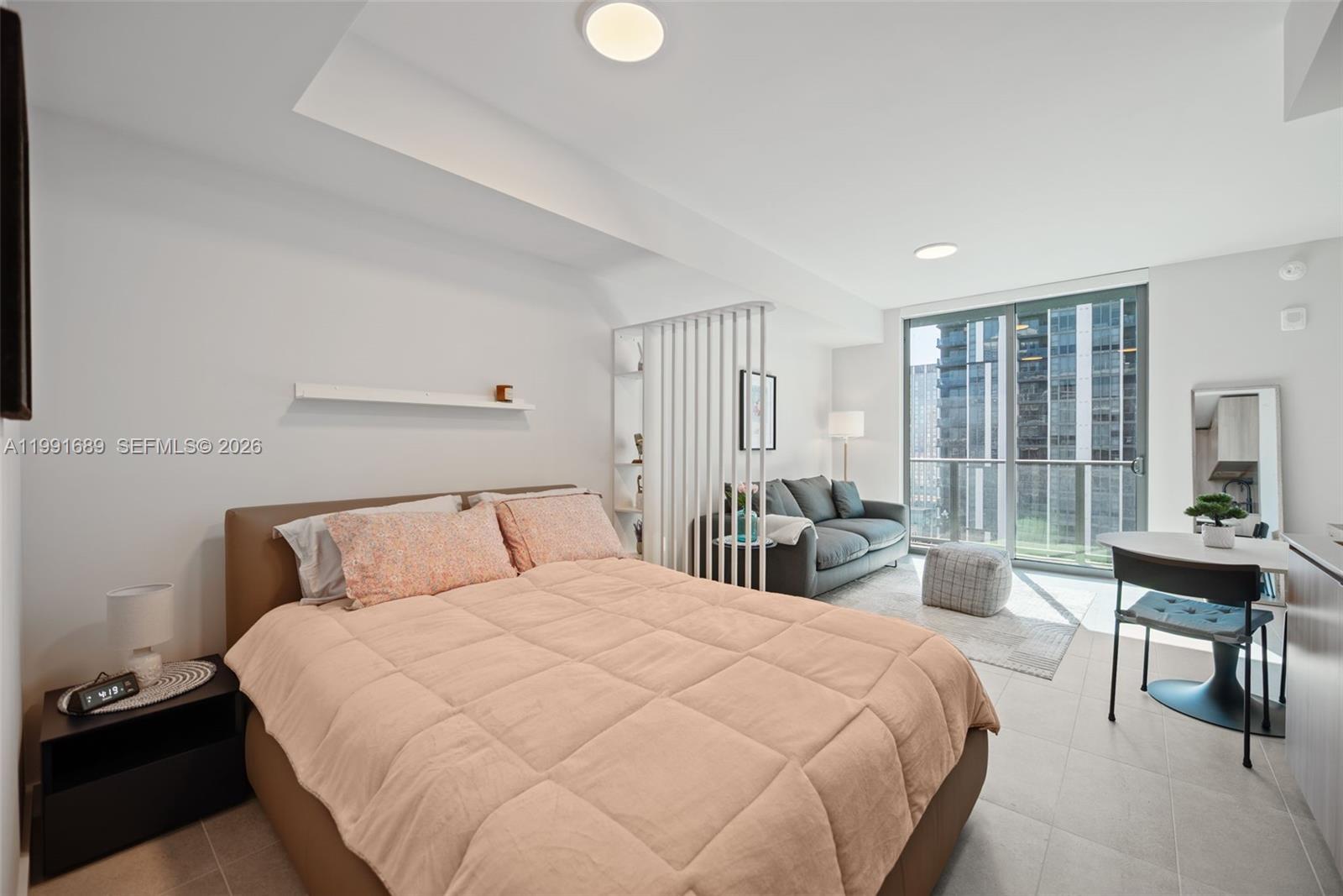 A studio apartment features a bed, a living area with a sofa, and floor-to-ceiling windows — 121 NE 5 ST # 3507, Miami FL 33132, MIAMI, FL