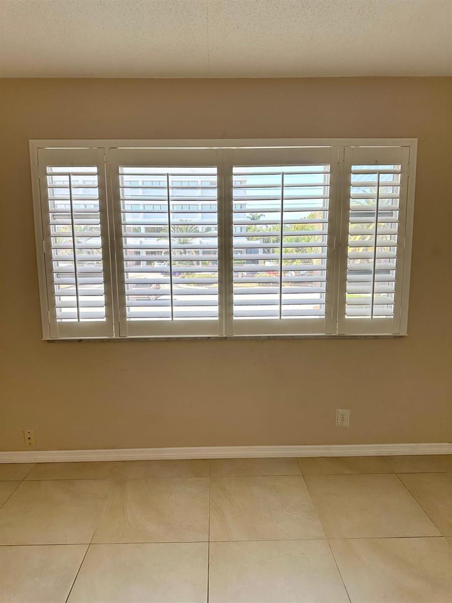 A room with beige walls, large tile flooring, and a window covered by white shutters — 350 S Cypress Road # 522, Pompano Beach FL 33060, POMPANO BEACH, FL