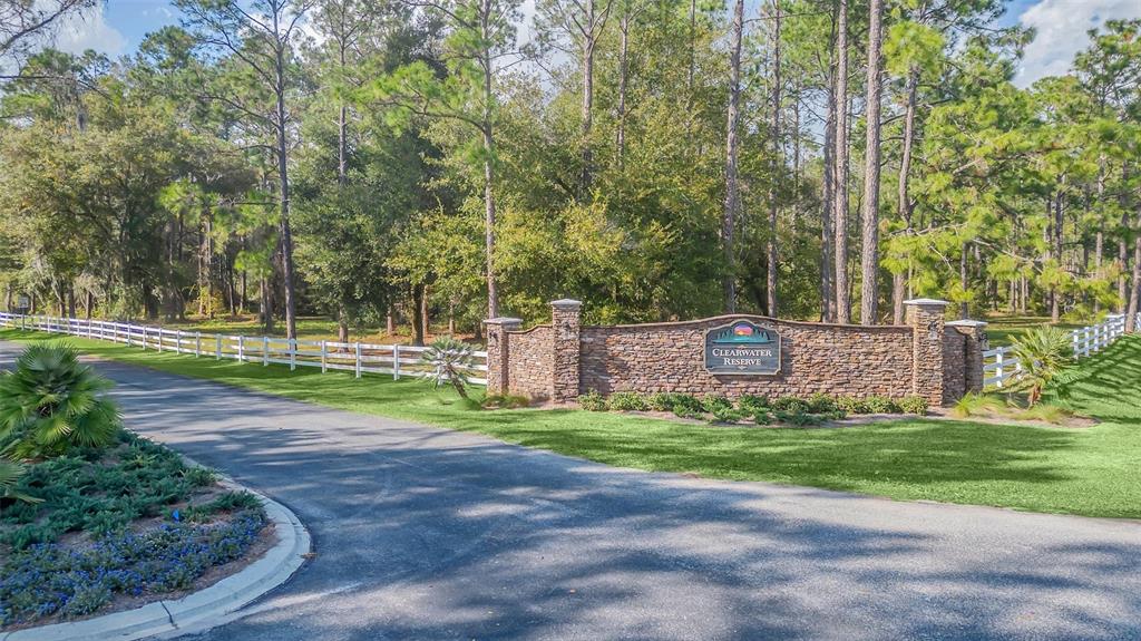 A stone entrance sign for Clearwater Reserve sits beside a paved road and white fence — 3106 BRIGHT LAKE CIRCLE, GROVELAND, FL