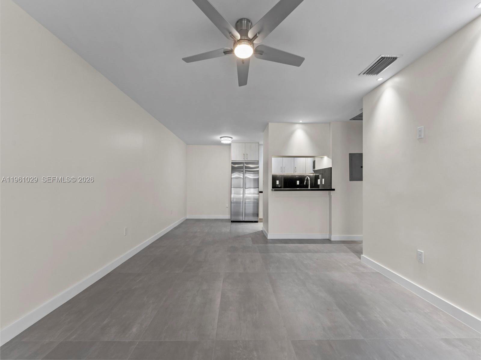 A minimalist room features gray tile flooring, a ceiling fan, and an open kitchen area — 15639 SW 73rd Cir Ter # 4, Miami FL 33193, MIAMI, FL