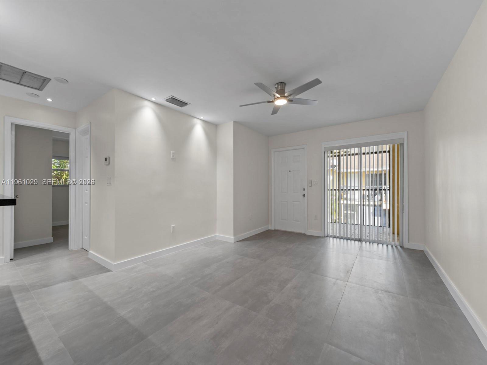 An empty room features gray tile flooring, a ceiling fan, and a sliding glass door — 15639 SW 73rd Cir Ter # 4, Miami FL 33193, MIAMI, FL