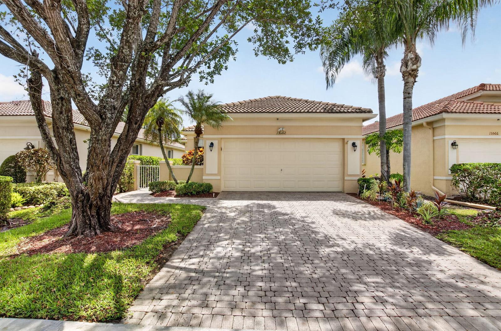 A single-story house with a beige stucco exterior, a tiled roof, and a paved driveway — 15562 Fiorenza Circle, Delray Beach FL 33446, DELRAY BEACH, FL