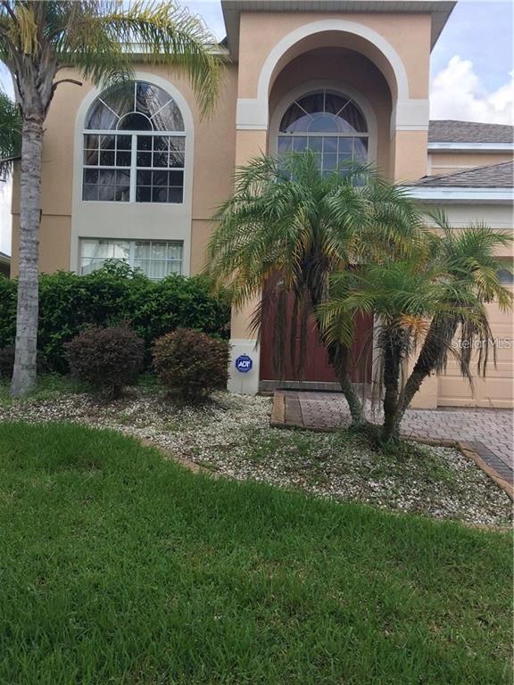 A two-story stucco house with arched windows, a palm tree, and a paved driveway — 5948 WINCHESTER ISLE ROAD, ORLANDO, FL