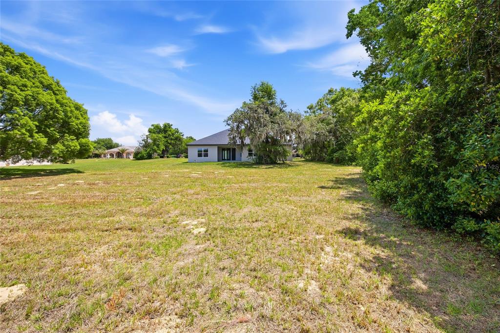 A single-story house sits in the distance behind a large, grassy, open lot — 464 N CHERRY POP DRIVE, INVERNESS, FL