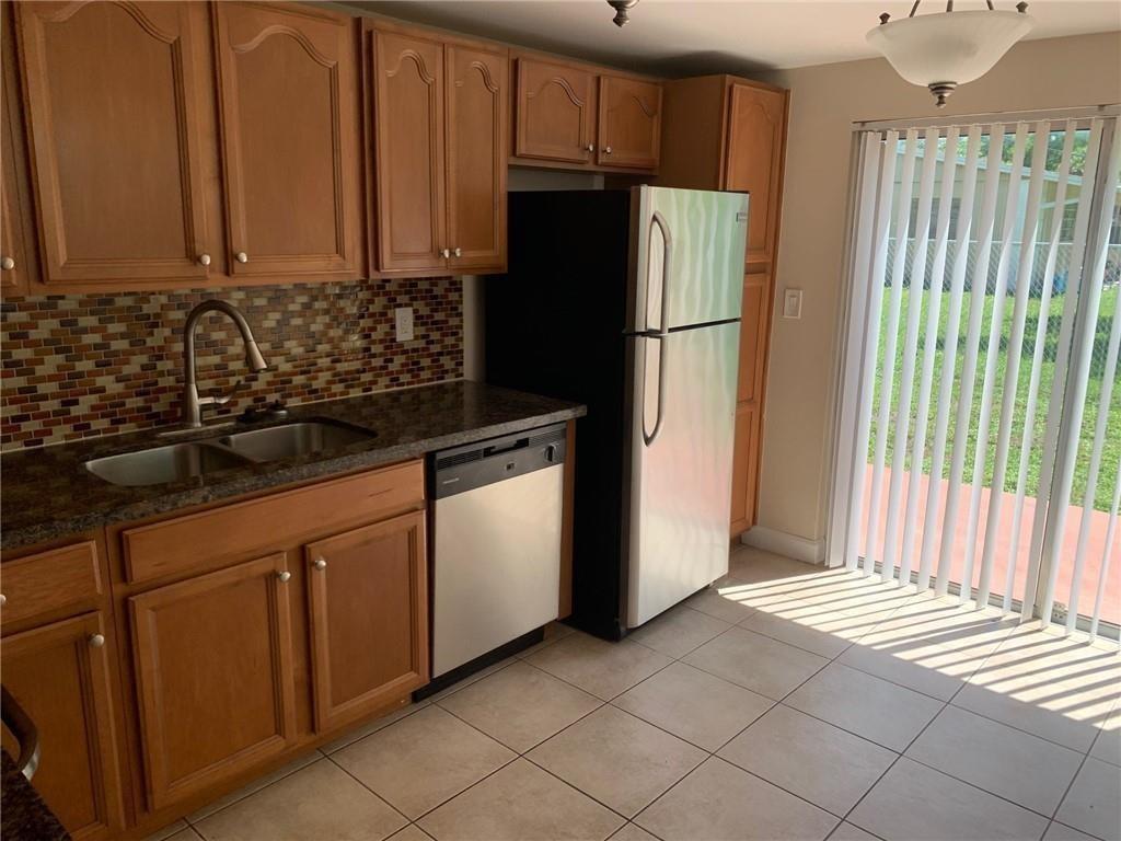 A kitchen features wood cabinets, a mosaic tile backsplash, stainless steel appliances, and tile flooring — 206 SW 1st Street # 4, Pompano Beach FL 33060, POMPANO BEACH, FL