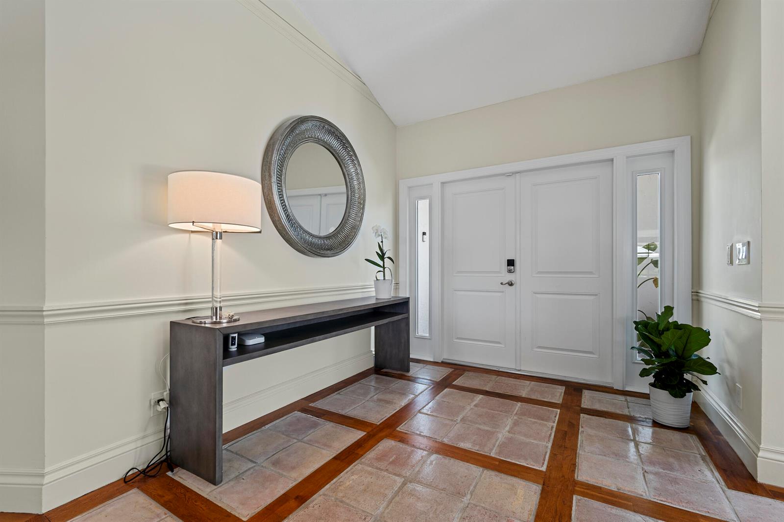 An entryway features a console table, a round mirror, and tiled flooring with wood trim — 10252 Shireoaks Lane, Boca Raton FL 33498, BOCA RATON, FL