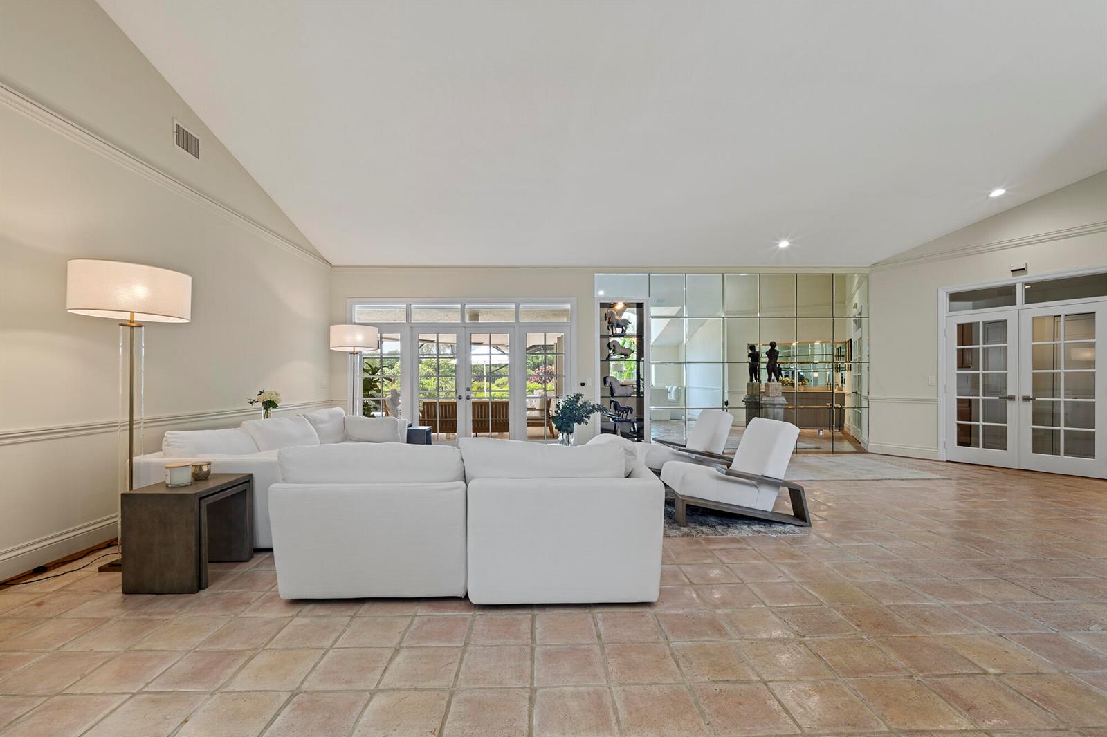 A spacious living room features white sofas, tiled floors, a mirrored wall, and glass doors — 10252 Shireoaks Lane, Boca Raton FL 33498, BOCA RATON, FL