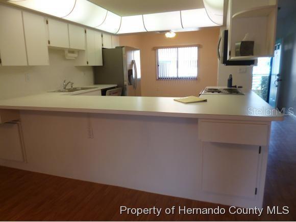 A kitchen with white cabinets, a breakfast bar, and stainless steel appliances — 6460 RIVER RUN BOULEVARD, WEEKI WACHEE, FL