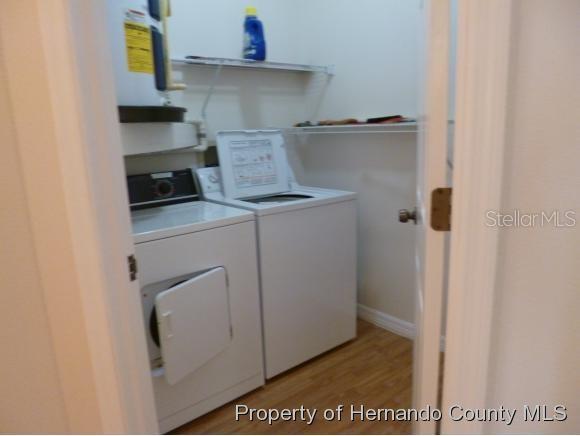 A laundry room features a washer, dryer, water heater, and wire shelving on the walls — 6460 RIVER RUN BOULEVARD, WEEKI WACHEE, FL