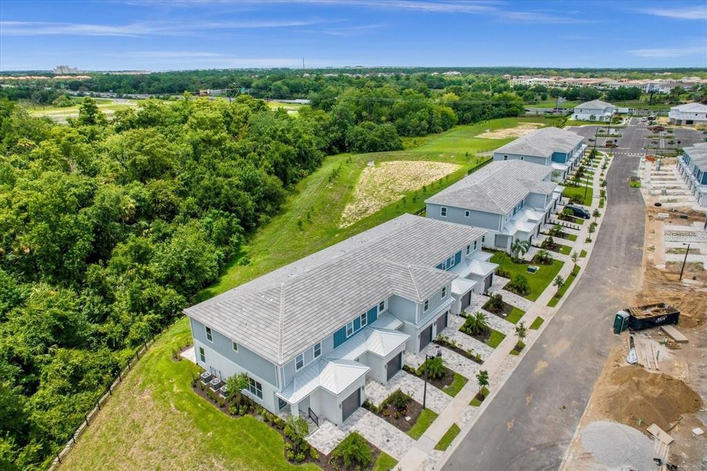An aerial view shows a row of newly constructed townhomes next to a wooded area — 7818 SPECTRUM DRIVE, KISSIMMEE, FL