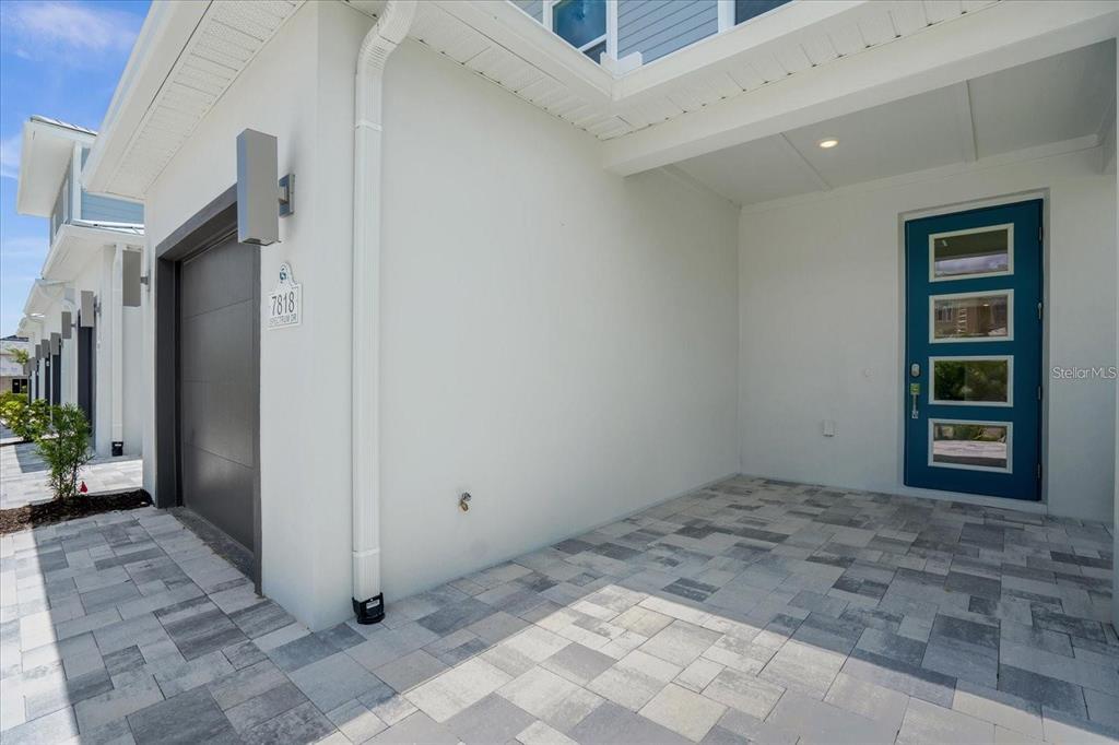 The exterior view shows a paved entryway with a teal front door and garage — 7818 SPECTRUM DRIVE, KISSIMMEE, FL